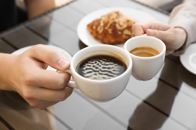 Photo of Man and woman drinking coffee at wooden table in outdoor cafe, closeup