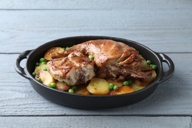 Tasty cooked rabbit with vegetables in baking dish on grey wooden table