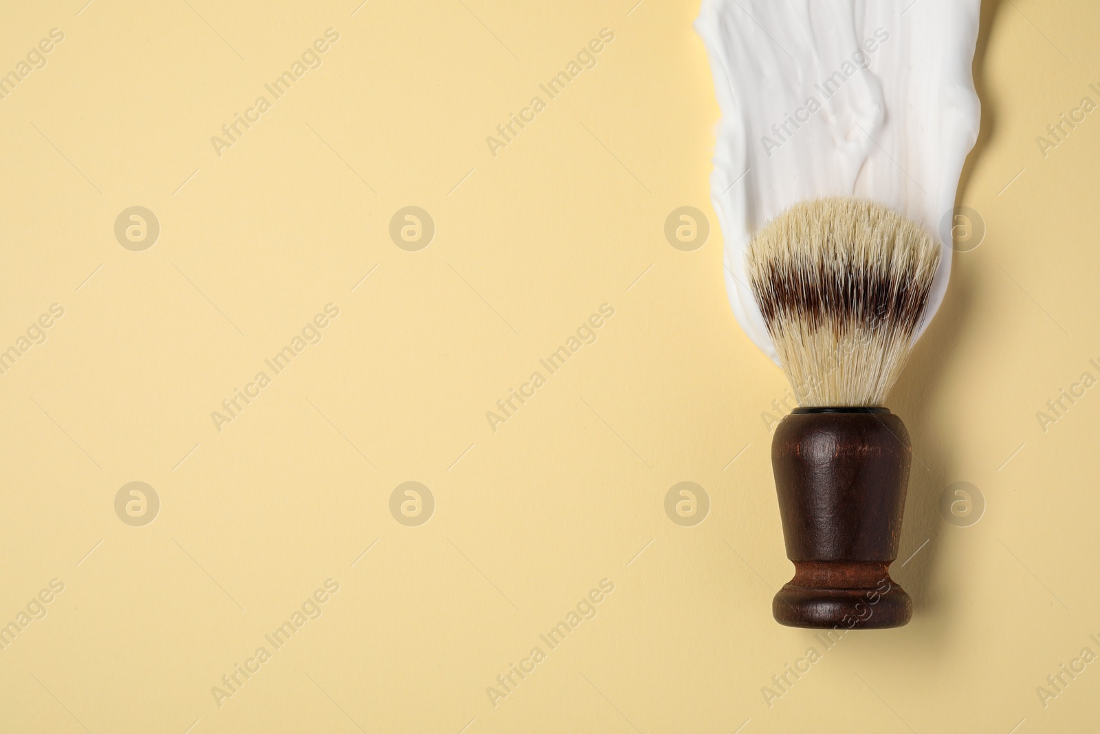 Photo of Brush with shaving foam on beige background, top view. Space for text