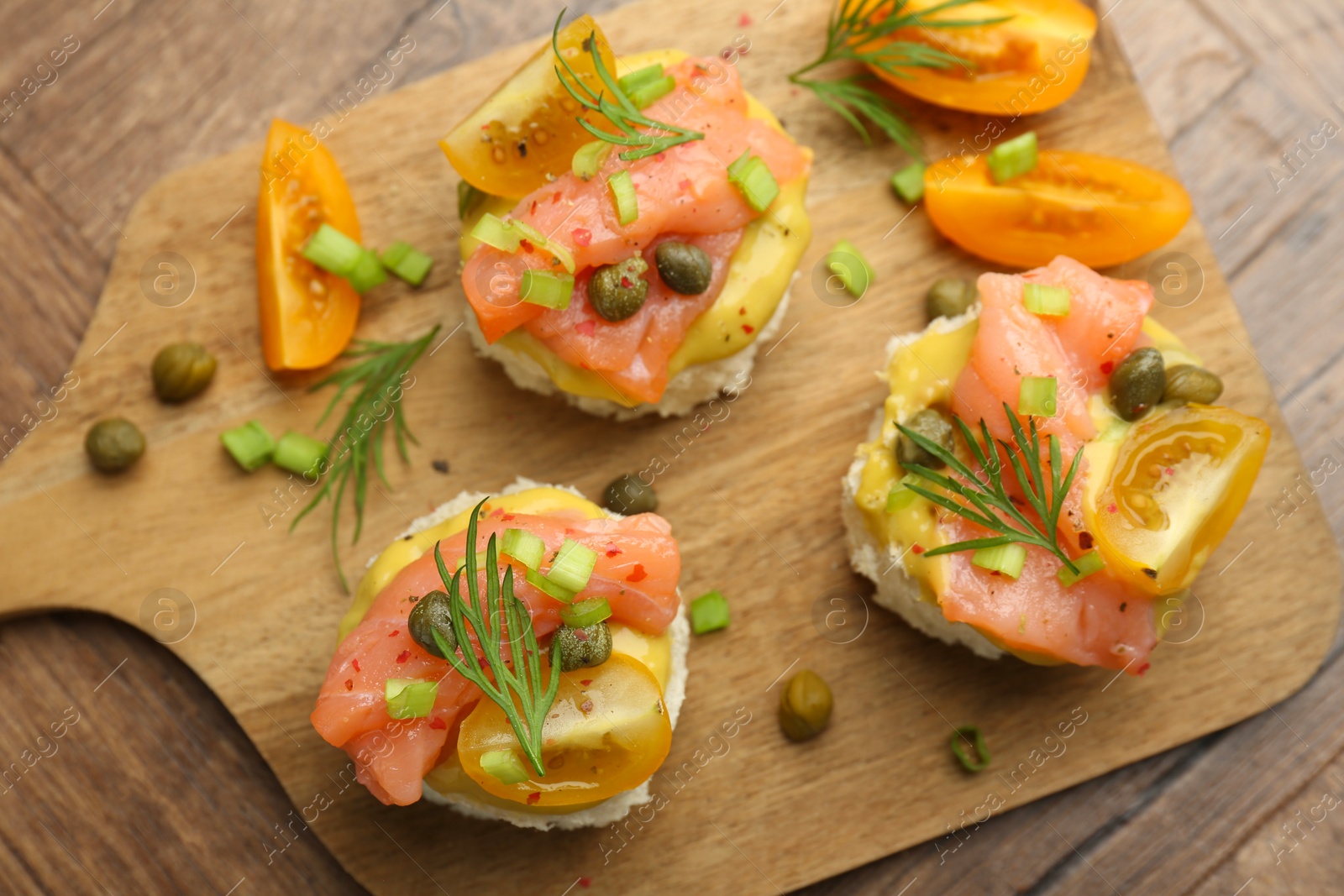 Photo of Tasty canapes with salmon served on wooden table, top view