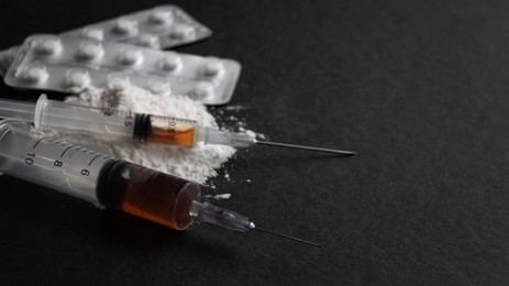 Syringes, pills and powder on black background, closeup with space for text. Hard drugs