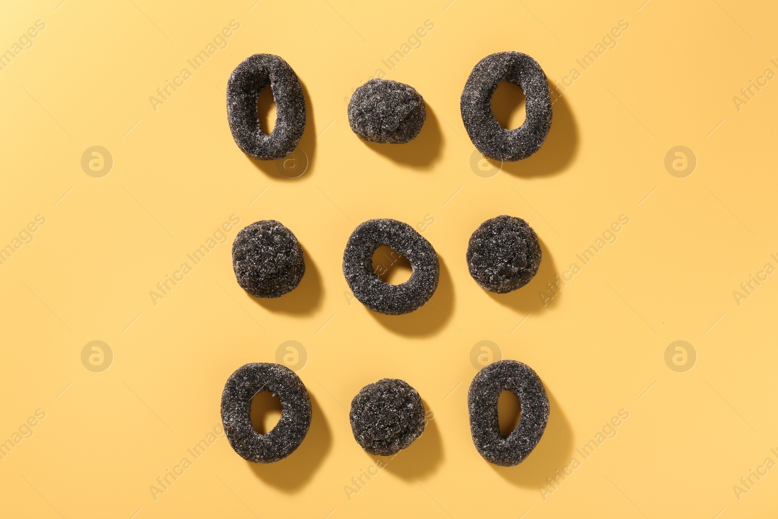 Photo of Tasty liquorice candies on yellow background, flat lay