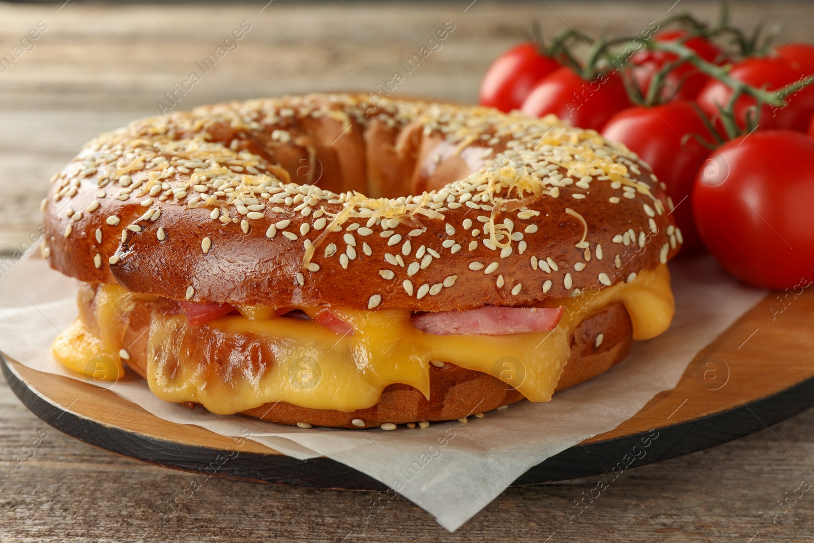 Photo of Delicious bagel with ham and cheese on wooden table, closeup