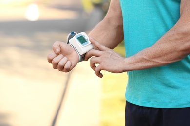 Photo of Young man checking pulse after workout, focus on hands