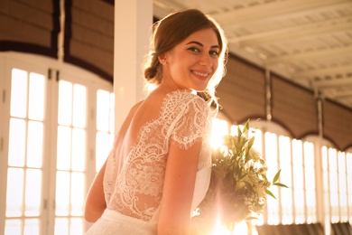 Photo of Gorgeous bride in beautiful wedding dress with bouquet indoors