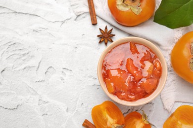 Bowl of tasty persimmon jam and ingredients on white textured table, flat lay. Space for text