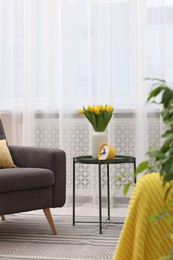 Spring atmosphere. Stylish living room interior with comfortable furniture and bouquet of beautiful yellow tulips