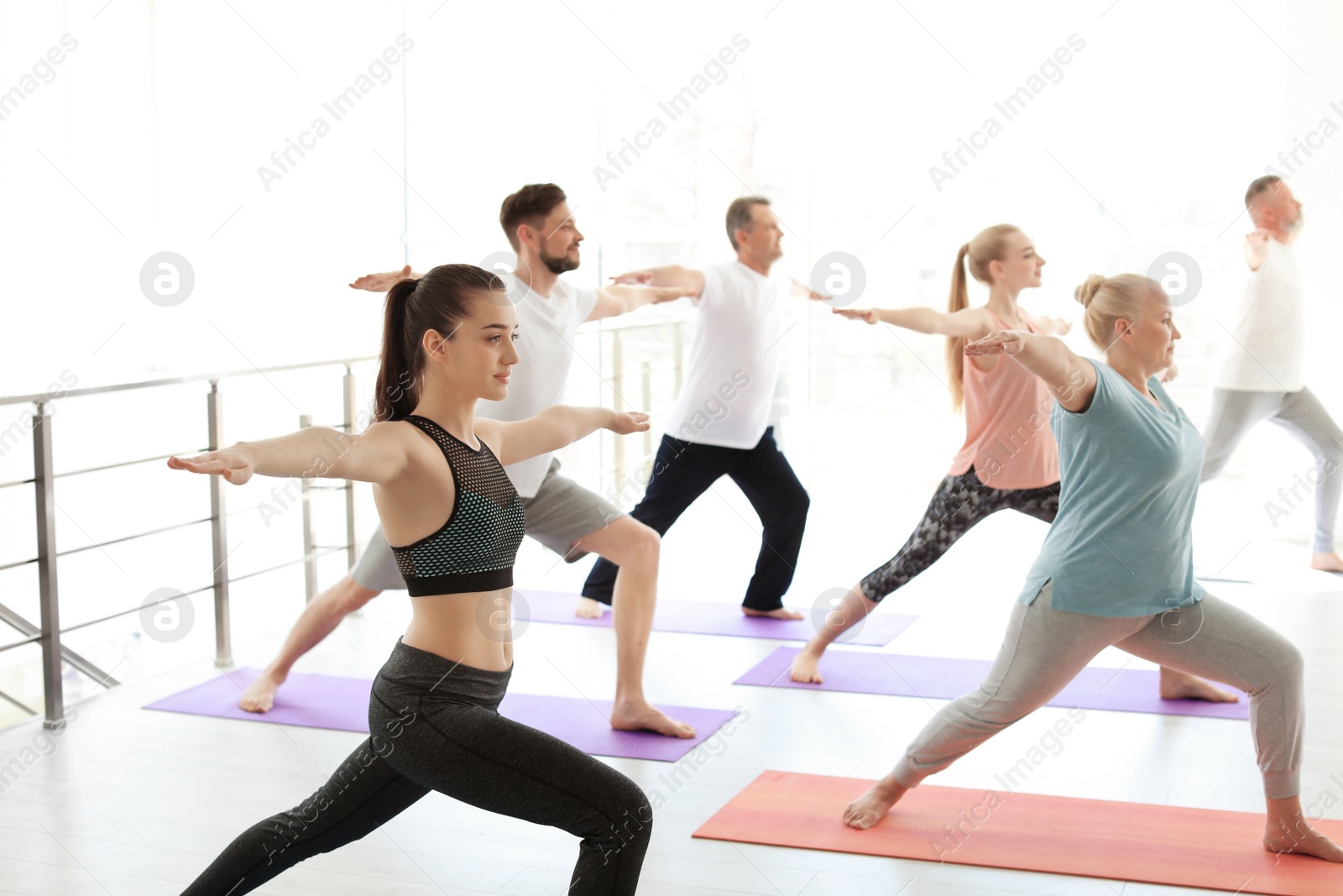 Photo of Group of people in sportswear practicing yoga indoors