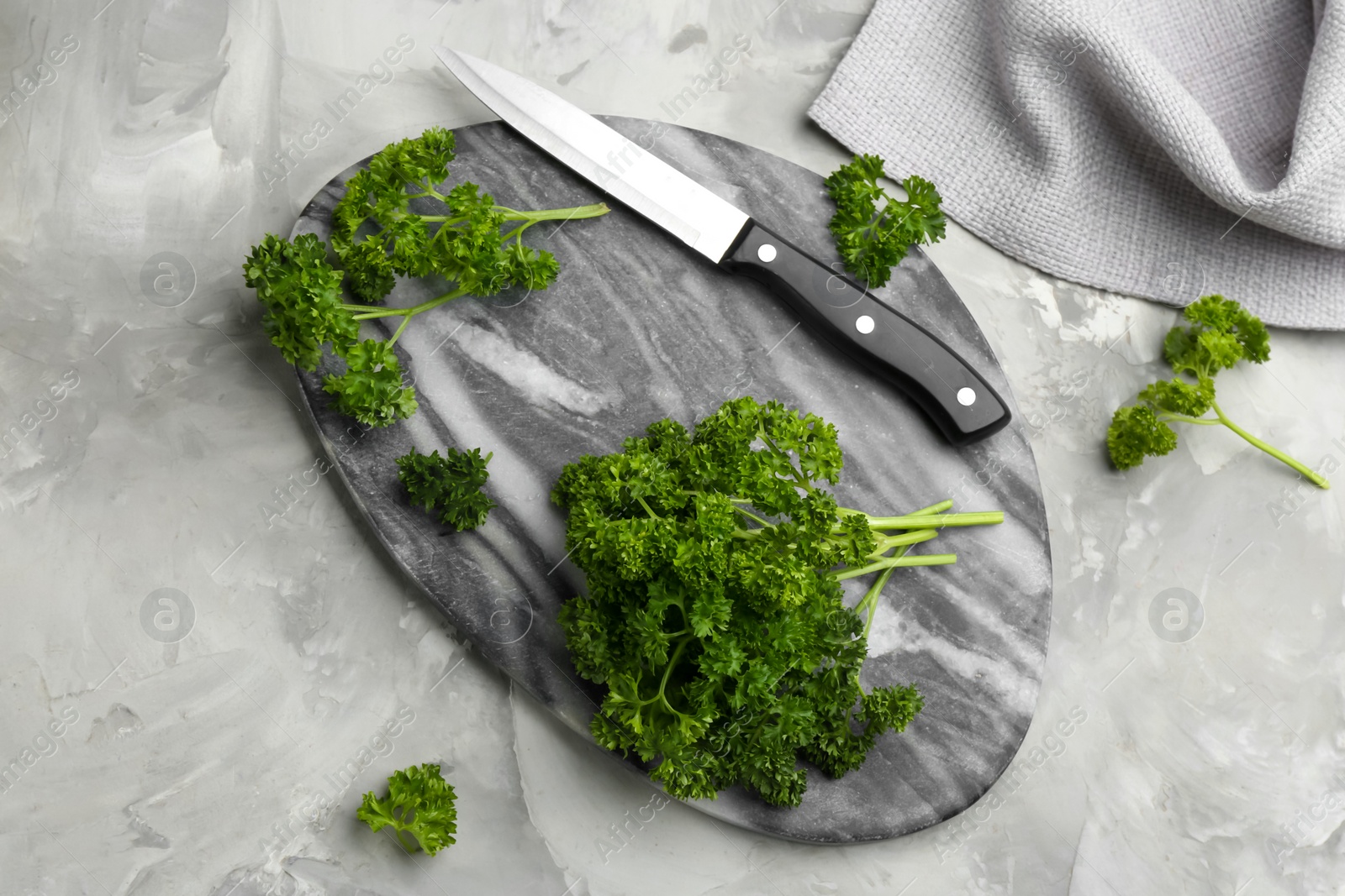 Photo of Fresh curly parsley, cutting board and knife on grey table, flat lay