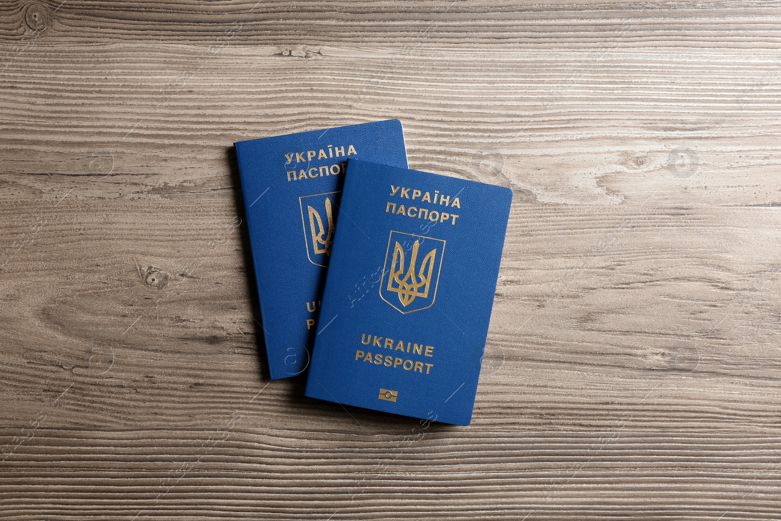 Photo of Ukrainian travel passports on wooden background, top view. International relationships