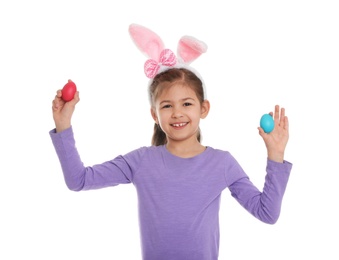 Photo of Little girl in bunny ears headband holding Easter eggs on white background