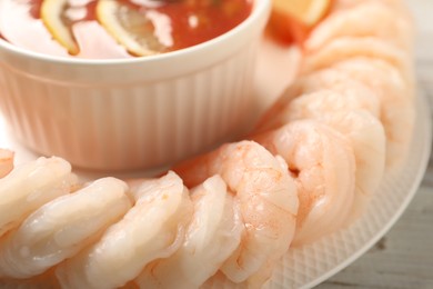 Photo of Tasty boiled shrimps with cocktail sauce and lemon on white wooden table, closeup