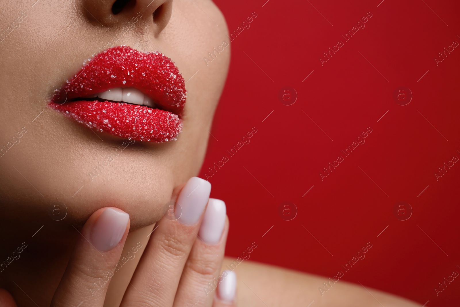 Photo of Closeup view of woman with lips covered in sugar on red background. Space for text