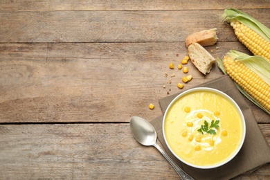 Delicious creamy corn soup served on wooden table, flat lay. Space for text