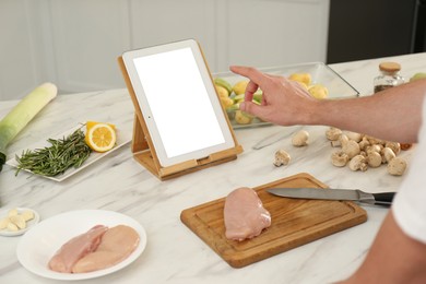 Man making dinner while watching online cooking course via tablet in kitchen, closeup