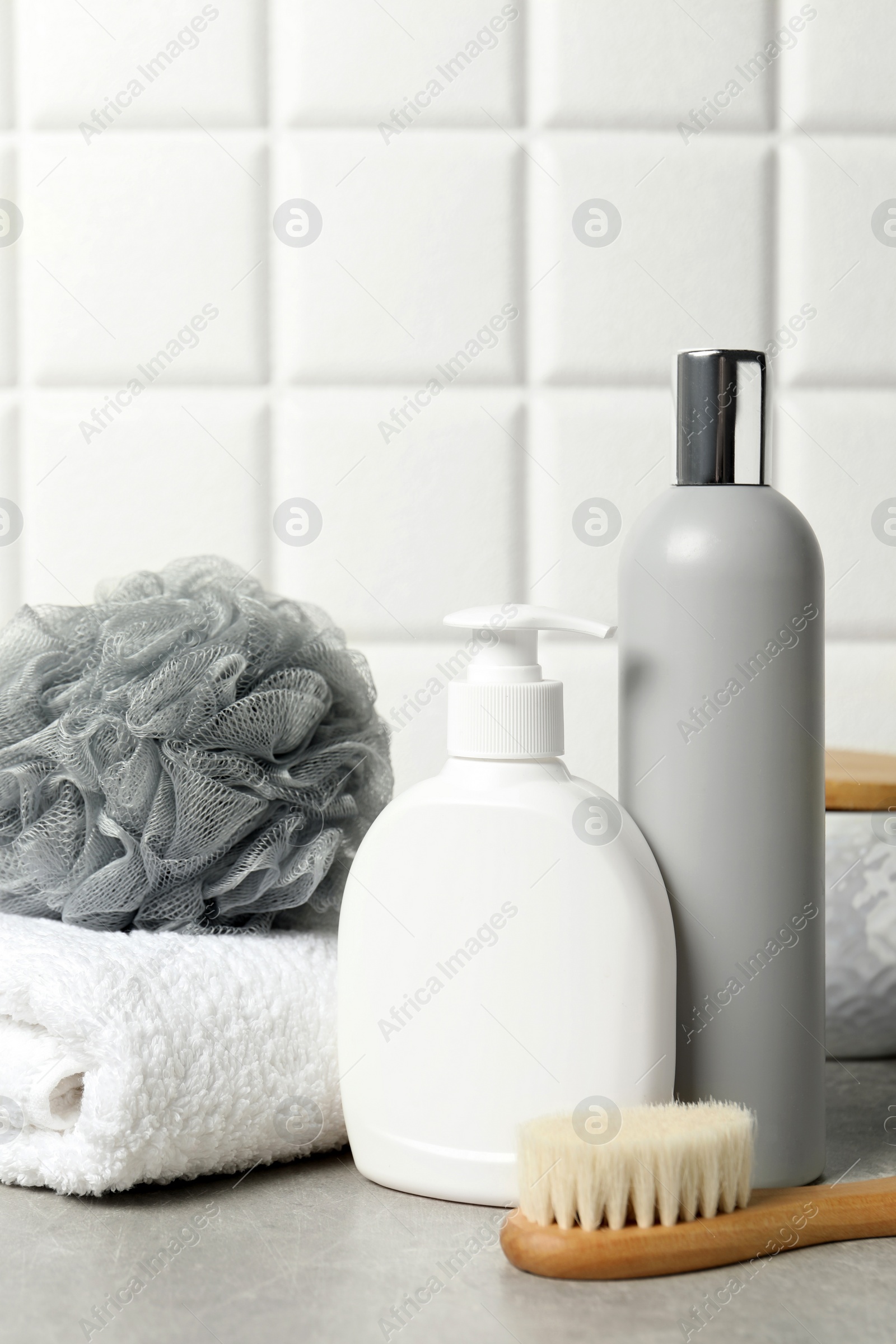 Photo of Different bath accessories and personal care products on gray table near white tiled wall