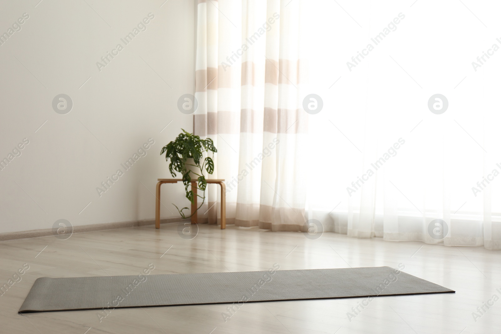 Photo of Unrolled grey yoga mat on floor in room