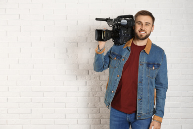 Photo of Operator with professional video camera near white brick wall, space for text