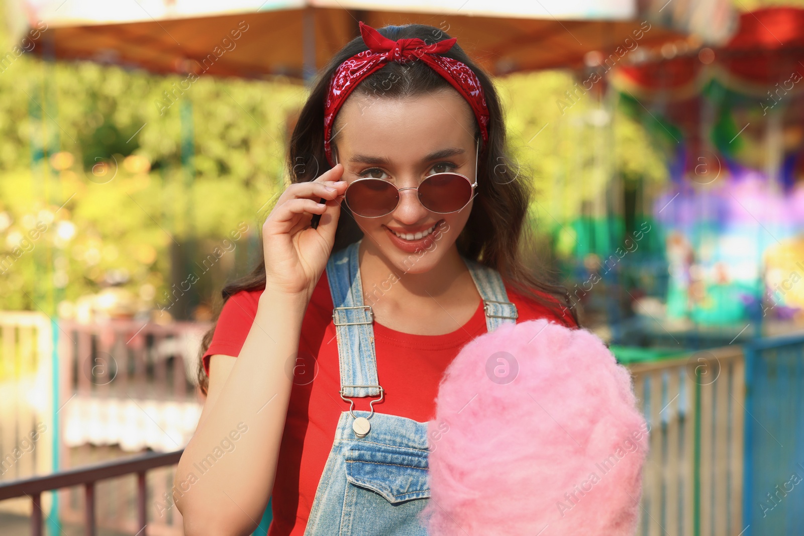 Photo of Stylish young woman with cotton candy outdoors