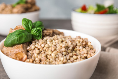 Photo of Bowl with tasty buckwheat porridge and meat, closeup