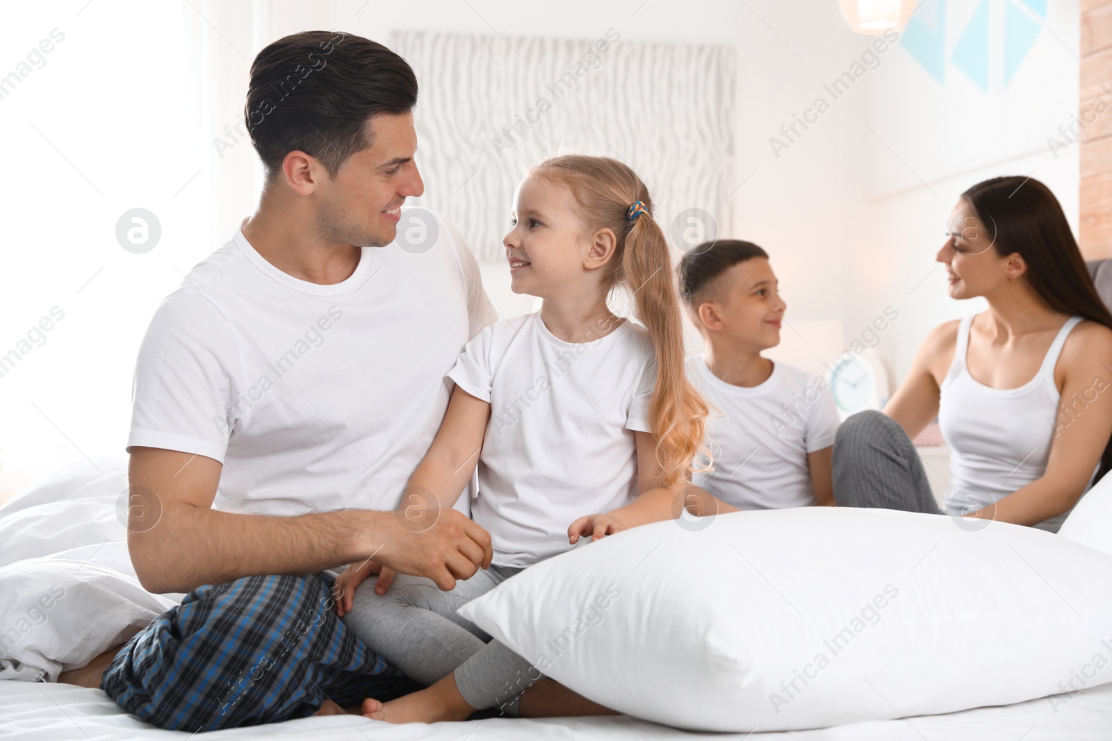 Photo of Happy young family together on large bed