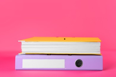 Bright hardcover office folders on pink background