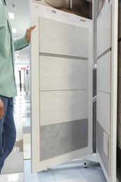 Photo of Man choosing tile among different samples in store, closeup