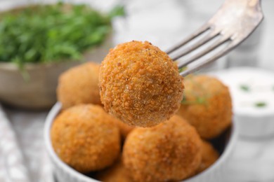 Photo of Taking delicious fried tofu ball with fork from bowl, closeup