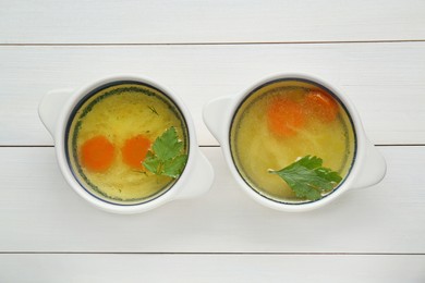 Delicious chicken bouillon with carrot and parsley on white wooden table, flat lay