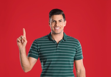 Photo of Man showing number one with his hand on red background