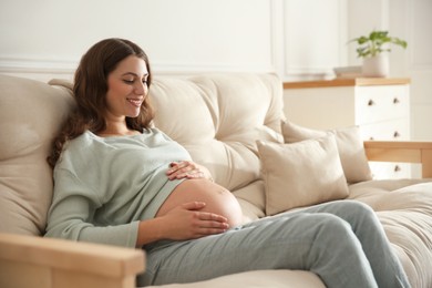 Photo of Happy pregnant woman touching her belly indoors