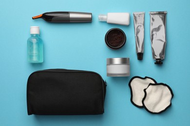 Photo of Preparation for spa. Compact toiletry bag with different cosmetic products on light blue background, flat lay