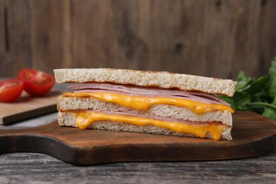 Photo of Delicious grilled sandwich with ham and cheese on wooden table, closeup