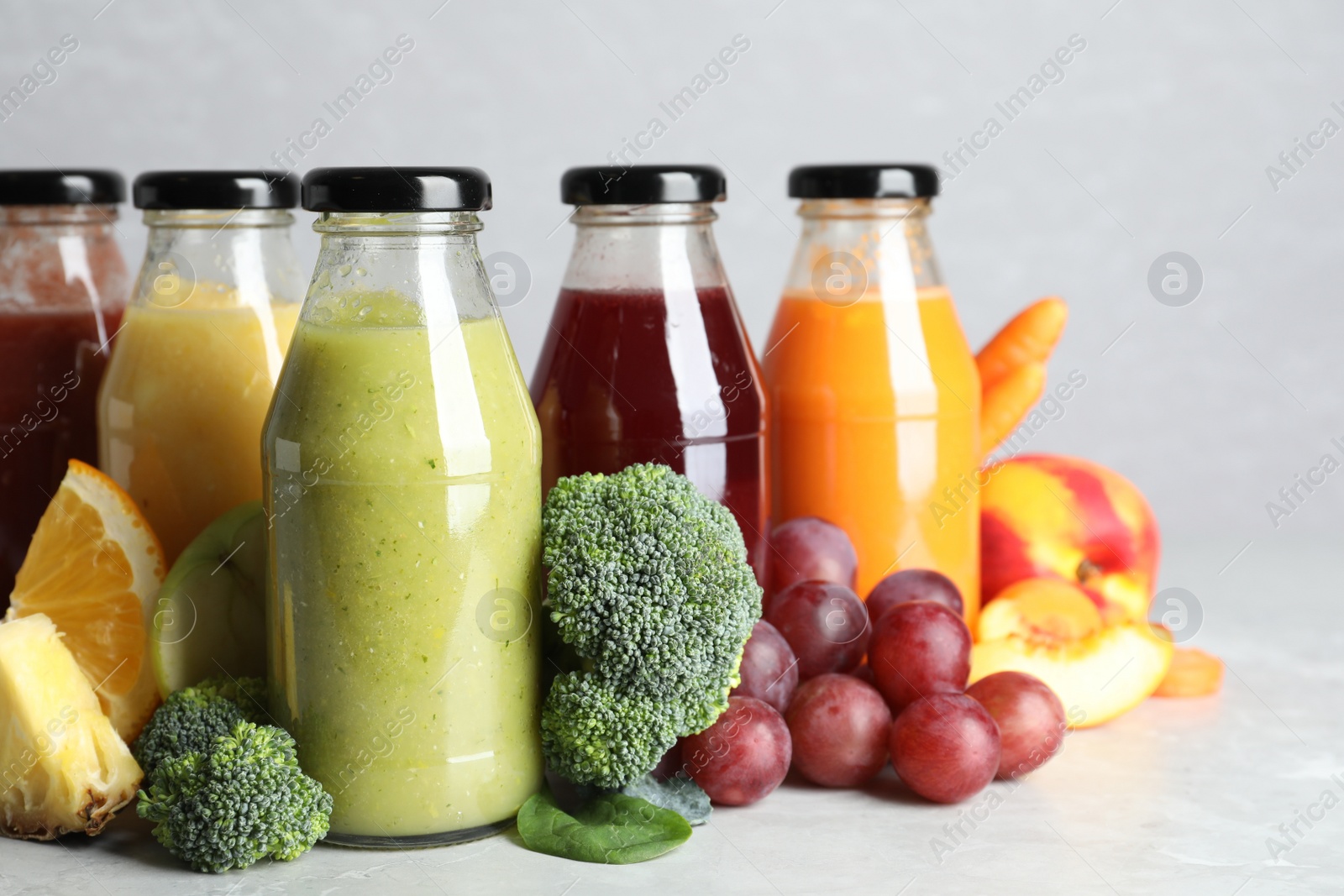 Photo of Bottles of delicious juices and fresh fruits on marble table