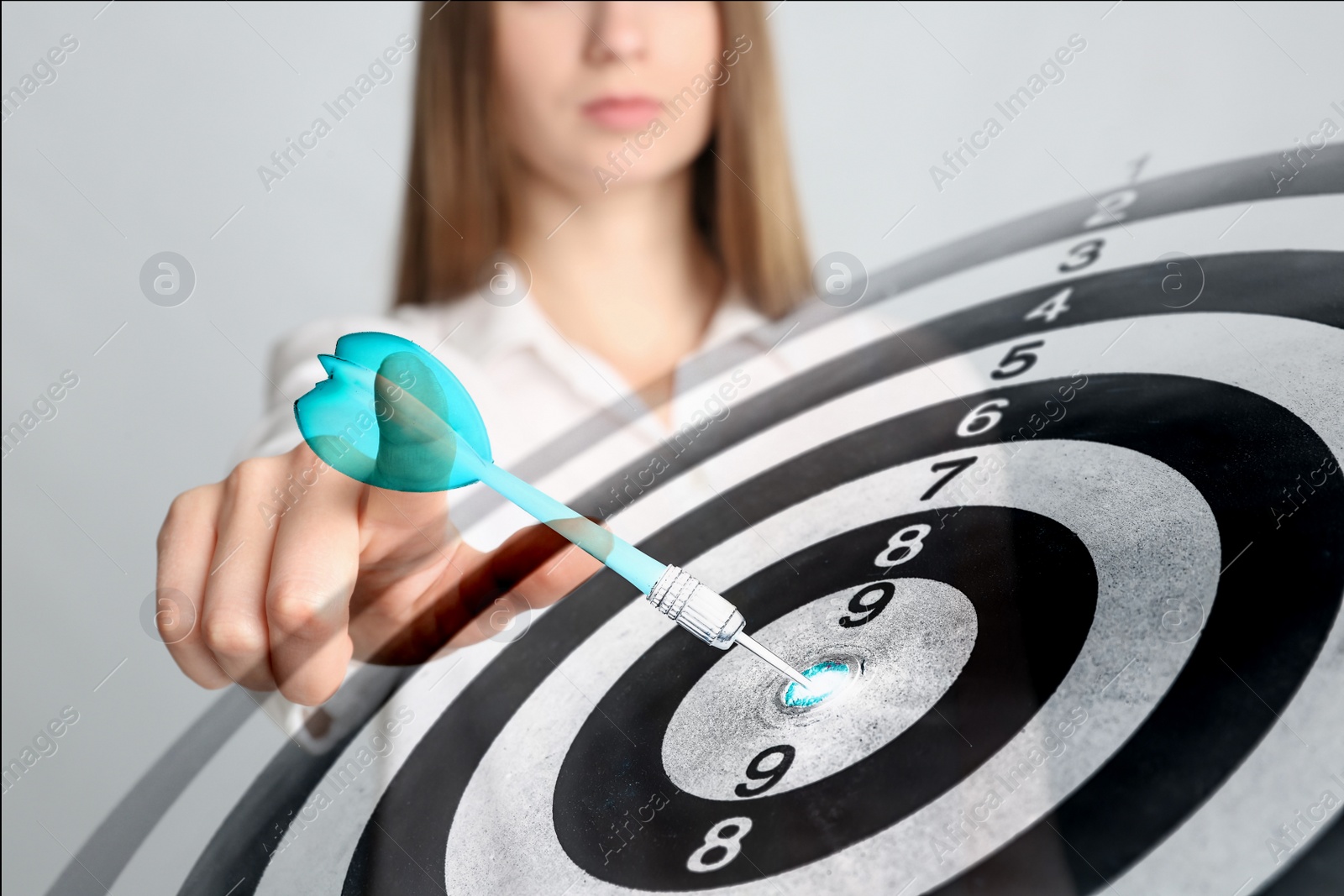 Image of Dartboard and young woman on light background, closeup