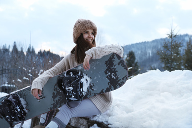 Photo of Young snowboarder wearing winter sport clothes outdoors