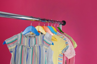 Photo of Rack with stylish children clothes on pink background, closeup