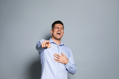 Handsome man laughing on grey background. Funny joke