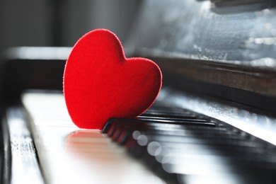 Photo of Small red decorative heart on piano keys, closeup. Space for text