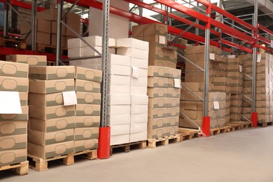 Photo of Warehouse with stacks of boxes on wooden pallets. Wholesaling