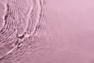 Photo of Rippled surface of clear water on pink background, top view