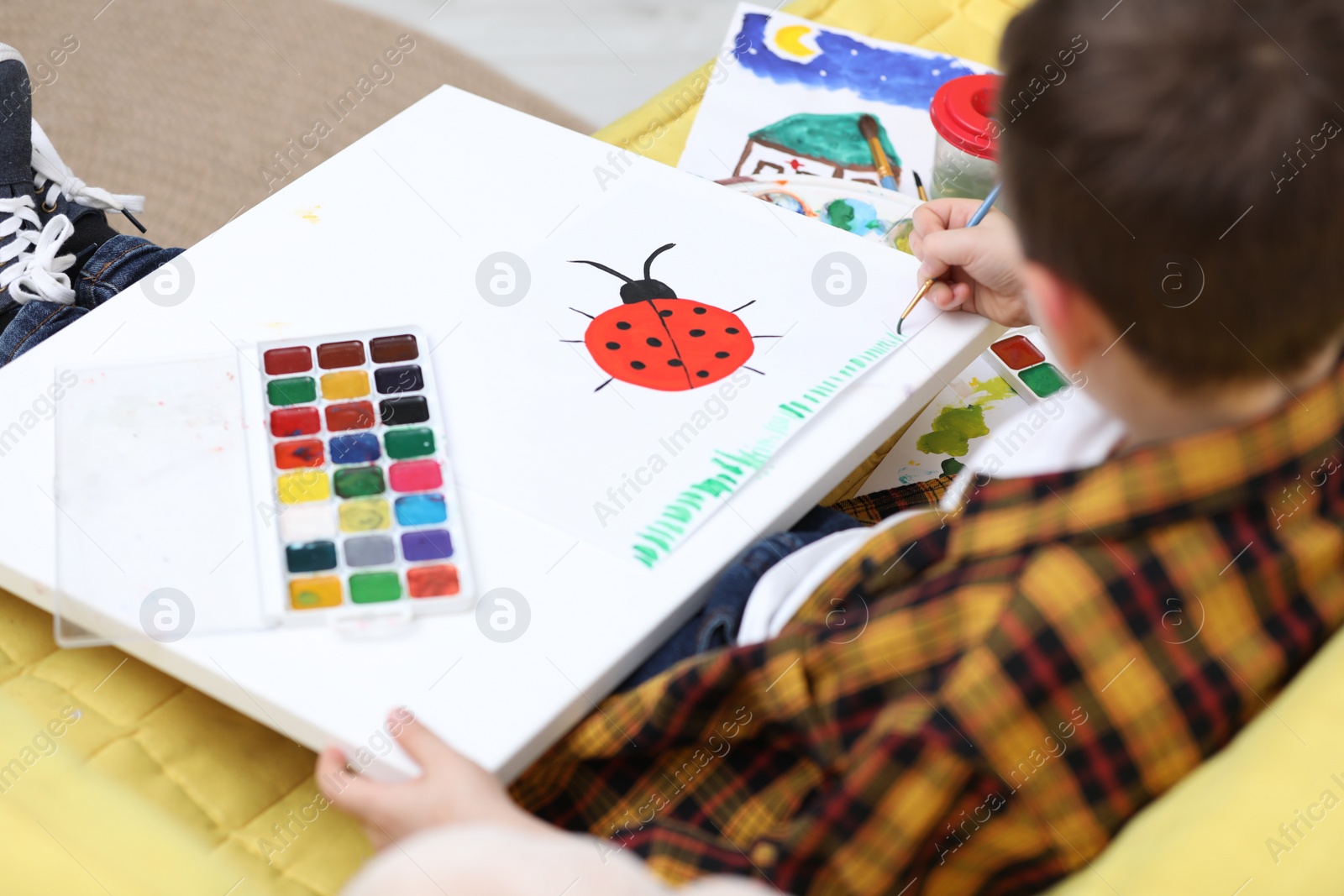 Photo of Little child painting on sofa at home