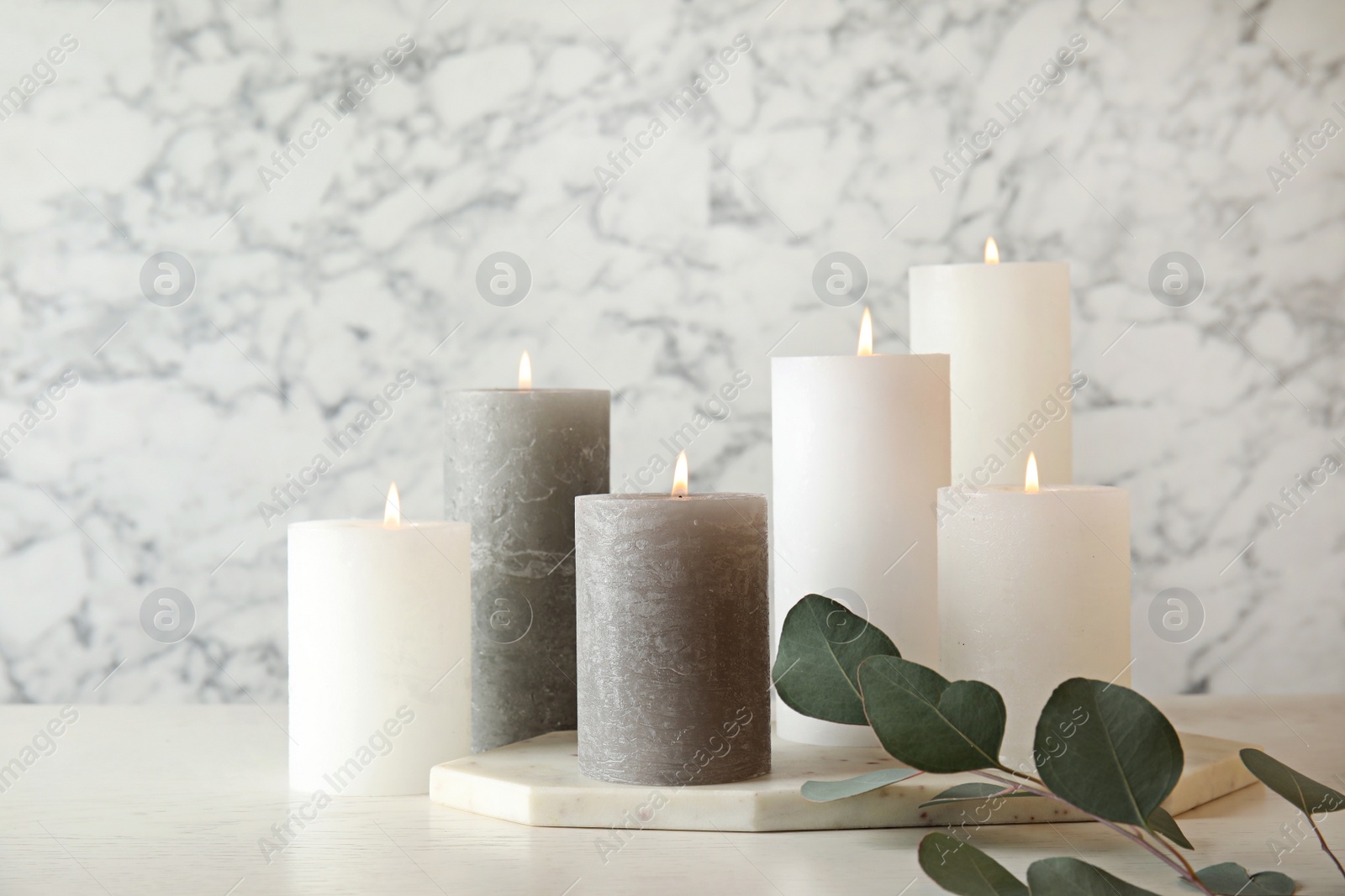 Photo of Composition with burning candles on table against marble background