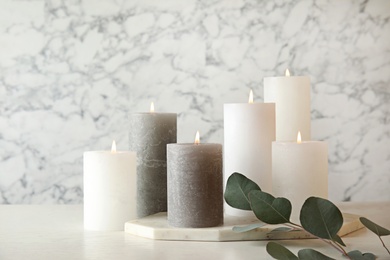 Composition with burning candles on table against marble background