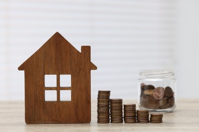 House model and stacked coins on wooden table