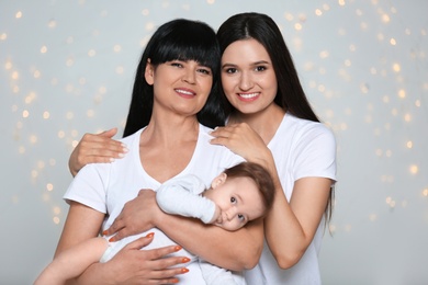 Photo of Portrait of young woman, her baby and mature mother against defocused lights