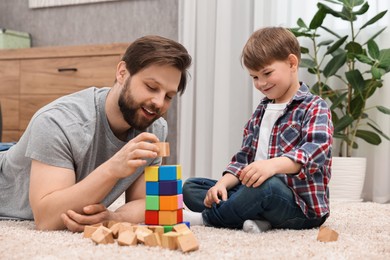 Happy dad and son building tower with cubes at home