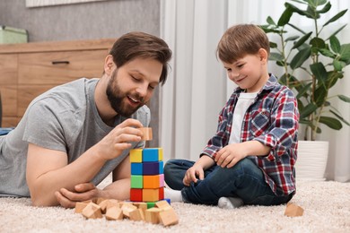 Photo of Happy dad and son building tower with cubes at home