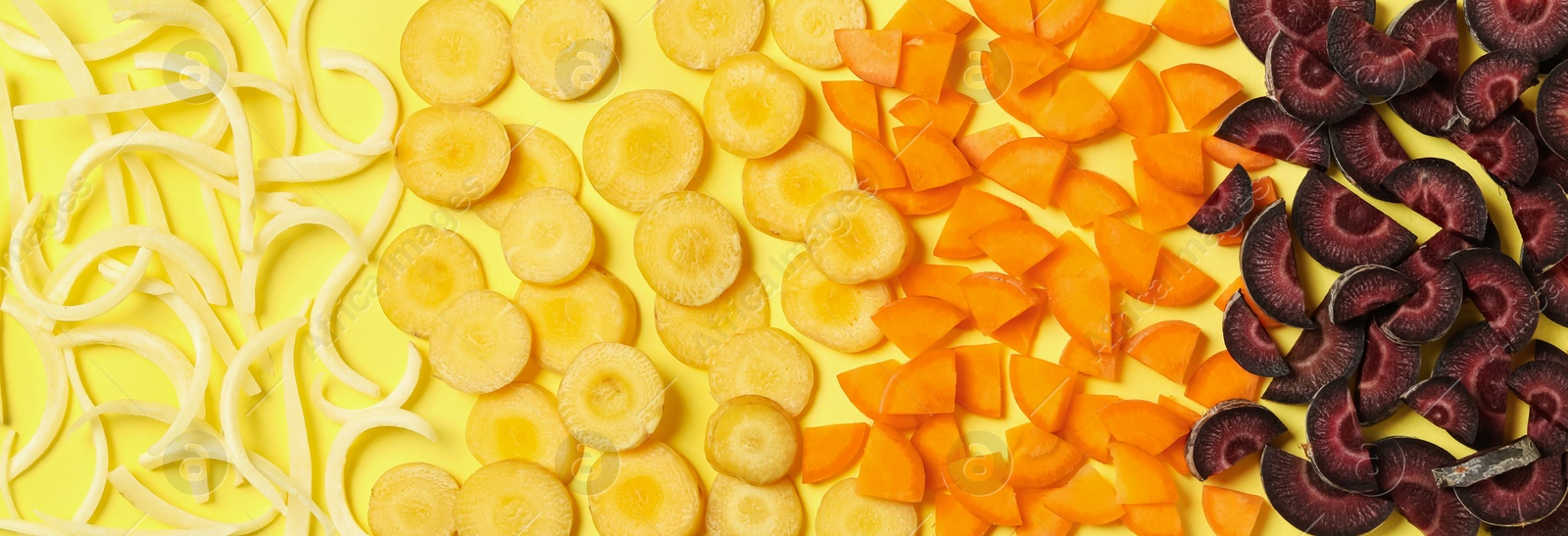 Photo of Pieces of raw color carrots on yellow background, flat lay