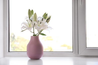 Photo of Vase of beautiful lilies on windowsill indoors, space for text